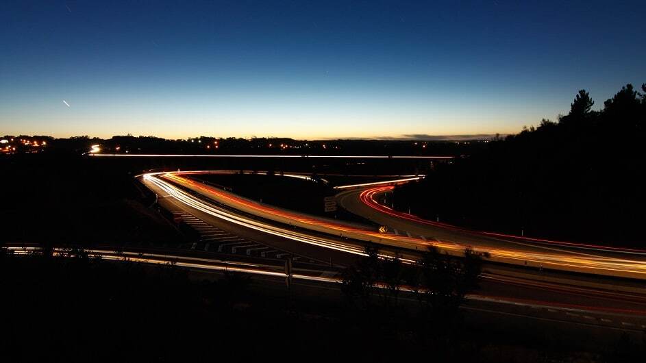 Autoestrada com uma saida e tr&aacute;fego leve durante o por do sol